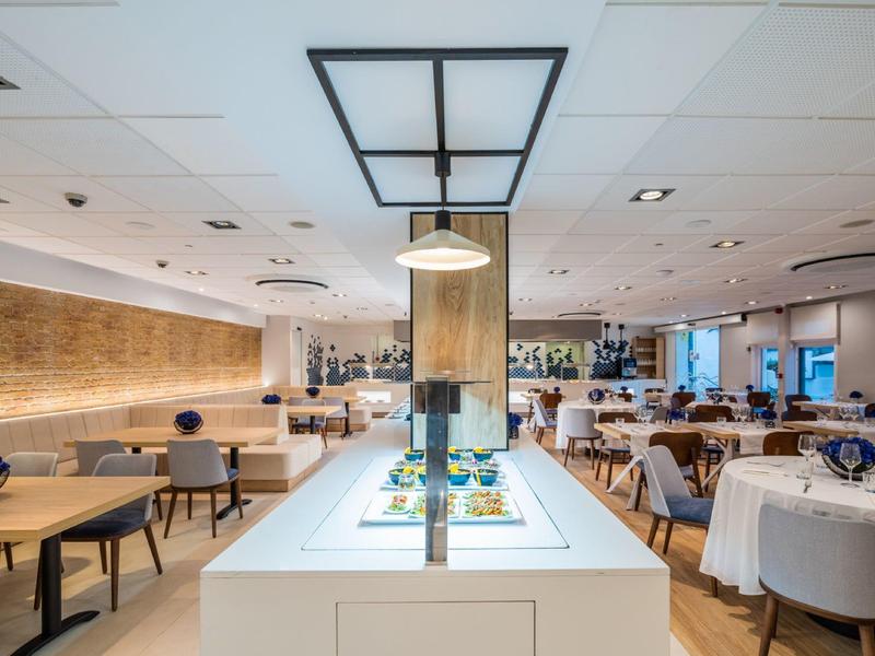 Moderní jídelna s prostřenými stoly a světlým osvětlením.