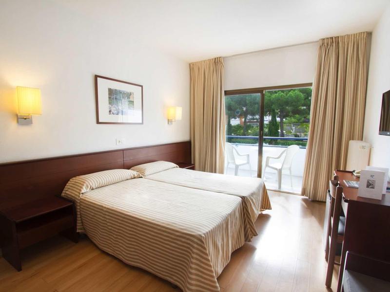 Camera d'hotel con letti singoli, pavimento in legno, balcone e luce soffusa