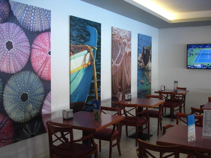 Accogliente zona pranzo con tavoli e sedie in legno, opere d'arte decorative e TV a parete.