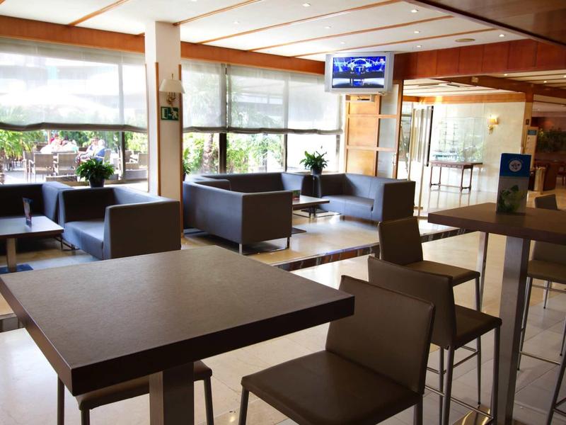 Lounge dell'hotel luminoso con mobili moderni e grandi finestre con vista sul verde.