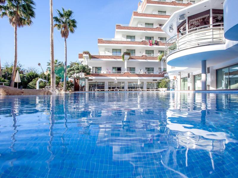 Moderner Hotelpool mit blauer Kachelumgebung und Palmen unter klarem Himmel