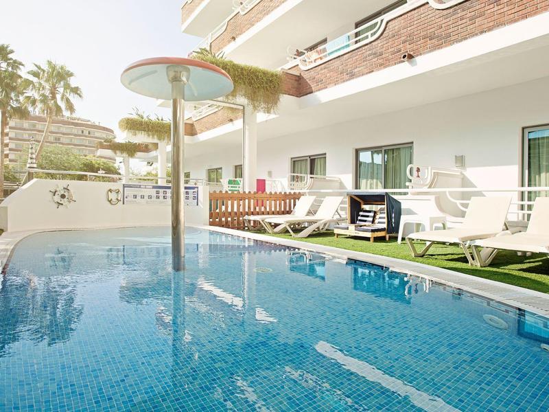 Moderner Außenpool mit Sonnenschirmen und Liegestühlen neben einem Hotelgebäude.