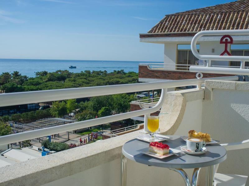 Balkon mit Tisch, Getränk und Snacks mit Blick auf das Meer und grüne Landschaft