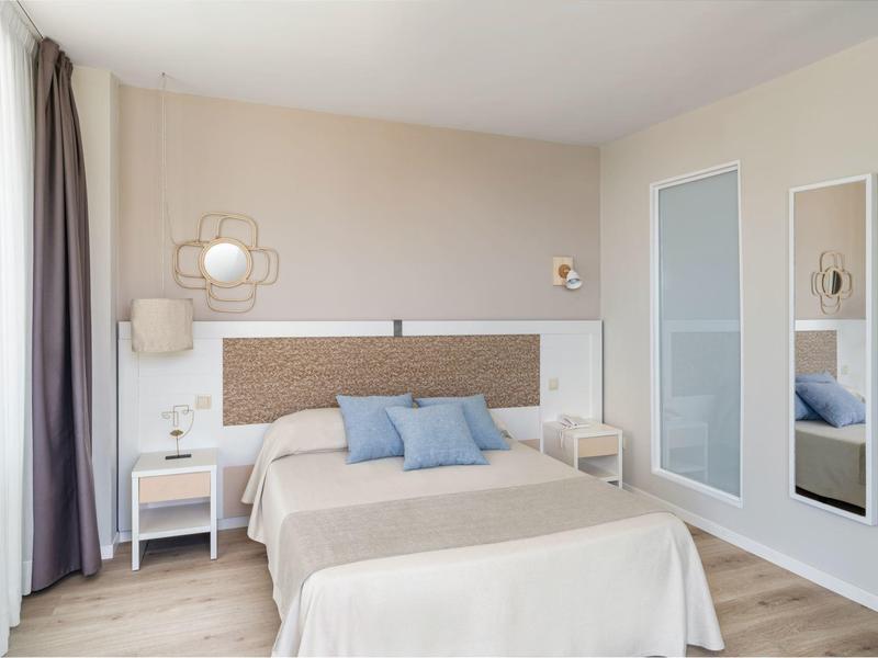 Helles, modernes Schlafzimmer mit Doppelbett, zwei Nachttischen und großem Spiegel an der Wand.