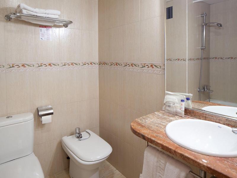 Compact bathroom with toilet, bidet, and sink with marble countertop.