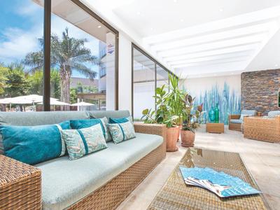 Světlá, moderní lounge s ratanovým nábytkem a modrými polštáři v hotelu.