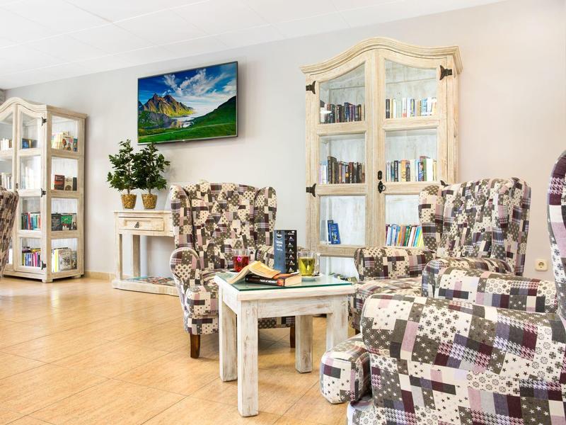 Světý obývací pokoj s křesly se vzorem a bílými vitrínami.