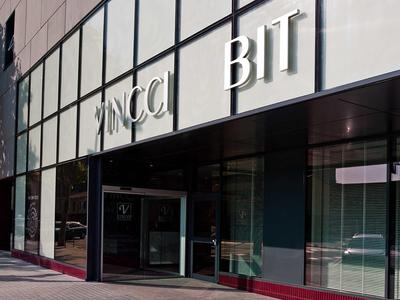 Gebäudefassade mit großen Glasfenstern und weißen, zurückgesetzten Buchstaben "ZANCCI BIT".