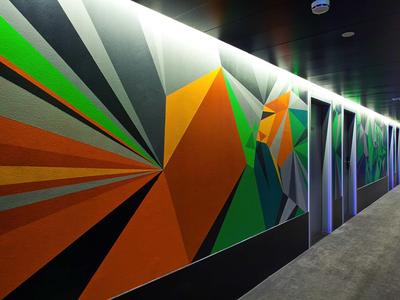 Langer Flur mit abstrakter Wandmalerei in kräftigen Farben wie Orange, Grün und Grau.