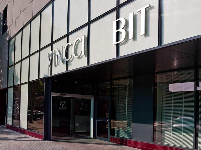 Gebäudefassade mit großen Glasfenstern und weißen, zurückgesetzten Buchstaben "ZANCCI BIT".