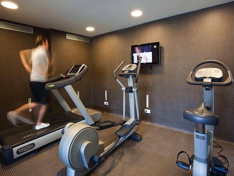 Ein Mann läuft auf einem Laufband in einem kleinen, modernen Fitnessraum mit mehreren Trainingsgeräten.