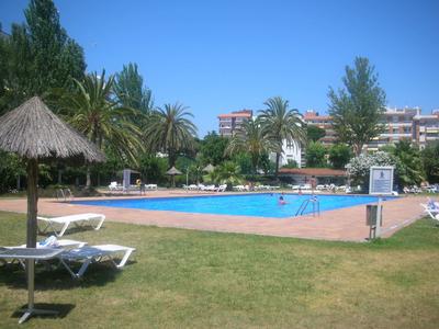 Grande piscina all'aperto con lettini e palme in area hotel soleggiata.