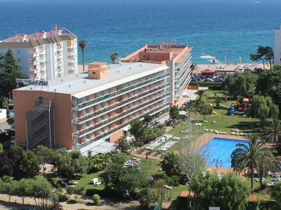 Edificio alberghiero di più piani con piscina e giardini vicino al mare.