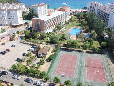 Vista di un'area hotel con campi da tennis, parcheggio, piscina e mare nelle vicinanze.