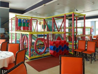 Parco giochi al coperto colorato in un ristorante con sedie arancioni e tavoli bianchi.