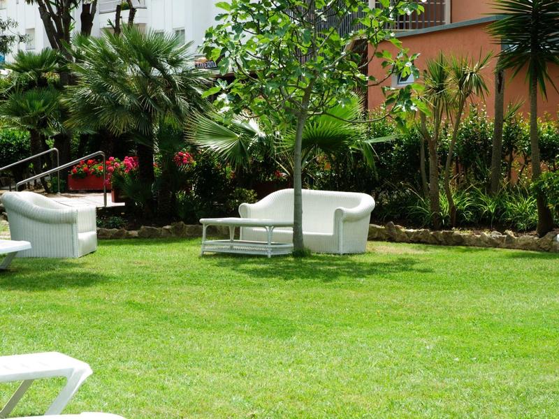 Prato verde con sedie bianche e vegetazione fitta sullo sfondo