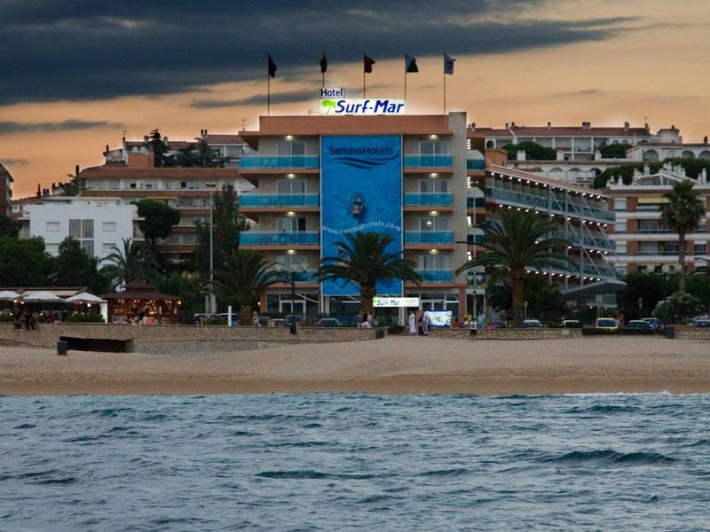 Hotel sulla spiaggia con sezione centrale blu e palme al tramonto