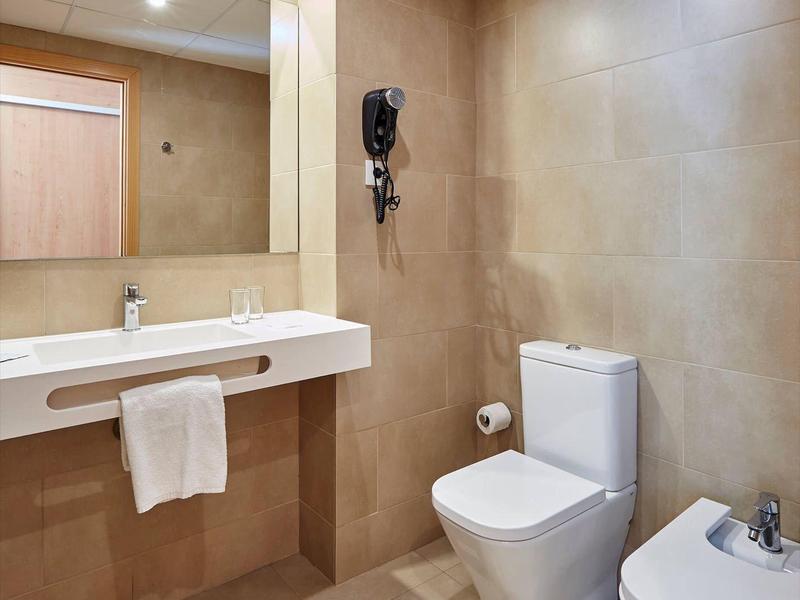 Bagno moderno con toilette, bidet, lavandino con specchio e telefono a parete.