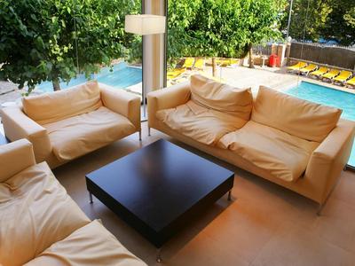 Gemütliche Sitzecke mit beigen Sofas und schwarzem Tisch neben einem Pool im Außenbereich.