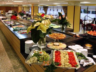 Großes Buffet mit Salaten, warmen Speisen und Blumenarrangements in hellem Speisesaal.