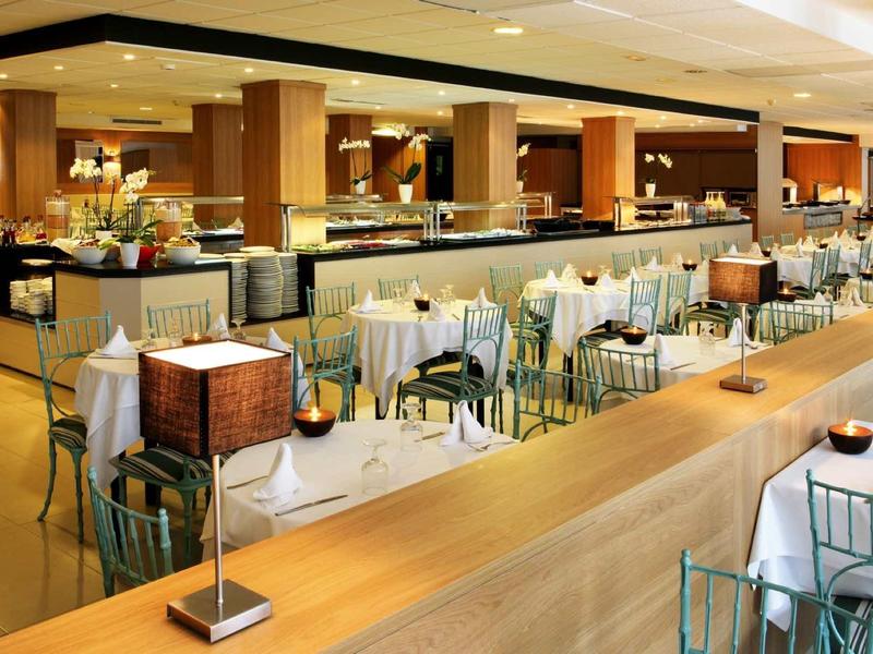 Elegantní hotelová jídelna s prostřenými stoly a moderním osvětlením.