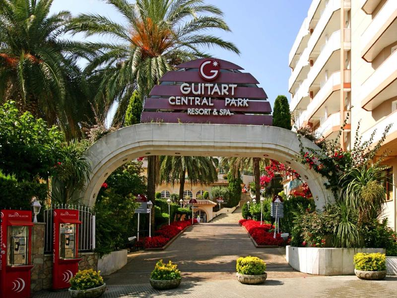 Vstup do Guitart Central Park Resort & Spa s palmami a květinovou výzdobou.