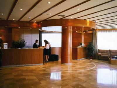 Elegante Hotellobby mit Holzelementen, Empfangstheke und Sitzbereich bei Tageslicht.