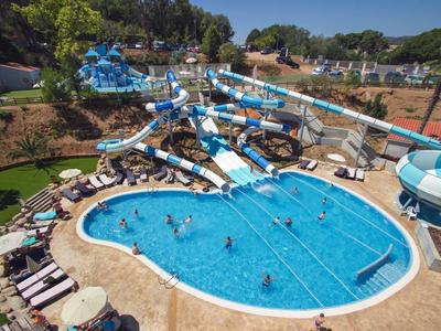 Wasserpark mit mehreren blauen Wasserrutschen und einem großen, unregelmäßigen blauen Pool.