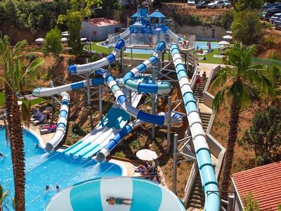 Wasserpark mit langen Rutschen und mehreren Pools, umgeben von Palmen.