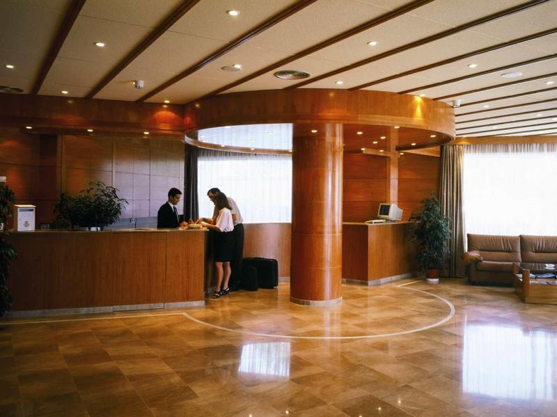 Elegante Hotellobby mit Holzelementen, Empfangstheke und Sitzbereich bei Tageslicht.