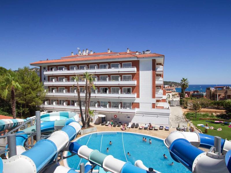 Großes Hotel mit blau-weißen Wasserrutschen und Außenpool unter strahlend blauem Himmel.