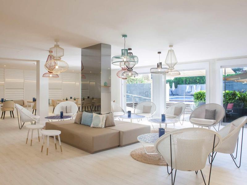 Modernes Wohnzimmer mit weißen Möbeln, großem Sofa, Glasfenstern und natürlicher Beleuchtung.