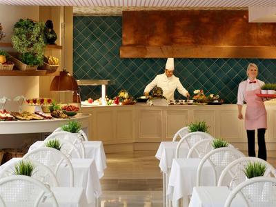 Elegant restaurant met wit gedekte tafels en koks bij de buffetbalie.