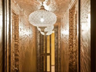 Couloir étroit et chaleureusement éclairé avec des lustres blancs complexes et des murs miroir.