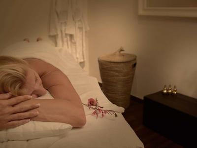 Femme se relaxant allongée lors d'un massage dans une pièce calme et chaleureusement éclairée.