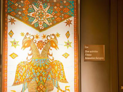 Une tapisserie colorée et ornée avec deux oiseaux stylisés et des étoiles dans un couloir d'hôtel.