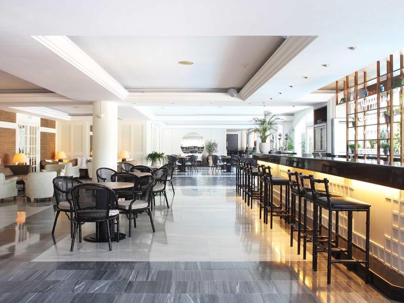 Restaurant d'hôtel moderne avec bar et espace de restauration, pièces lumineuses et mobilier élégant.