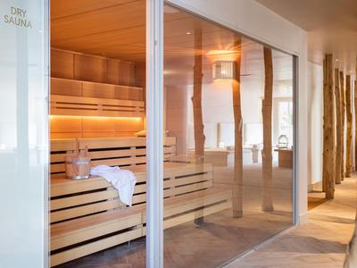 Sauna luminosa y moderna con bancos de madera y paredes de vidrio en un hotel spa.