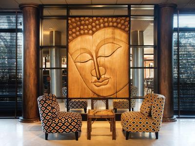 Angolo salotto con due poltrone a motivi e grande opera d'arte in legno.