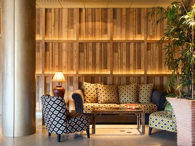 Sala de estar de hotel con sillones estampados, mesa de centro y pared de madera decorativa.