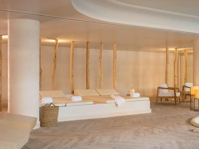 Spa moderno con luz cálida, camillas blancas y decoración minimalista.