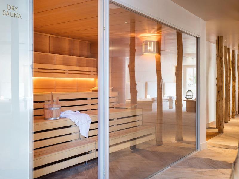 Sauna luminosa y moderna con bancos de madera y paredes de vidrio en un hotel spa.