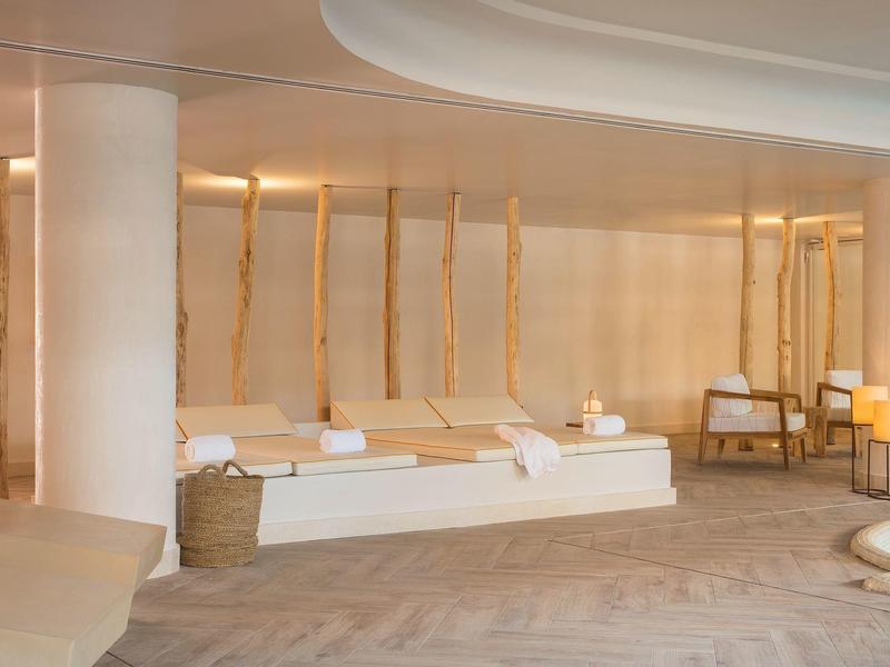 Spa moderno con luz cálida, camillas blancas y decoración minimalista.