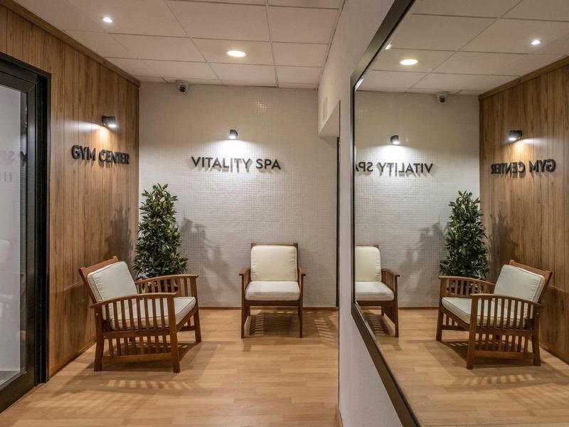 Zona de spa acogedora con dos sillones, paredes de madera y grandes espejos.