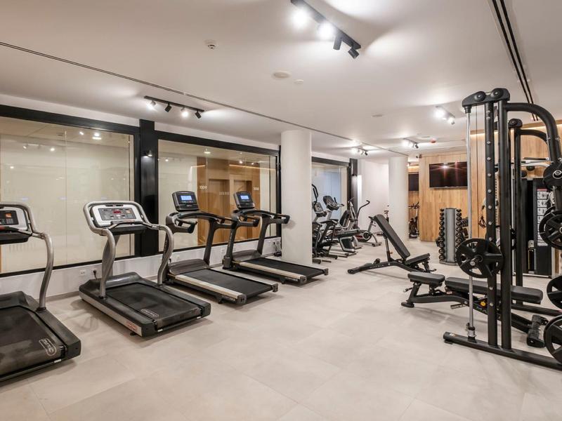 Gimnasio moderno con cintas de correr, máquinas de fuerza y grandes ventanas.