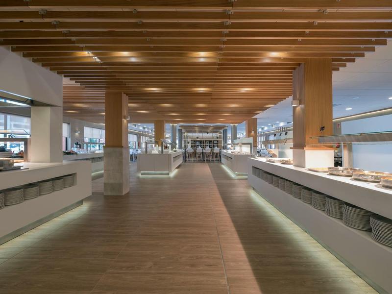 Amplio comedor moderno con techo de madera y largas estaciones de buffet a ambos lados.