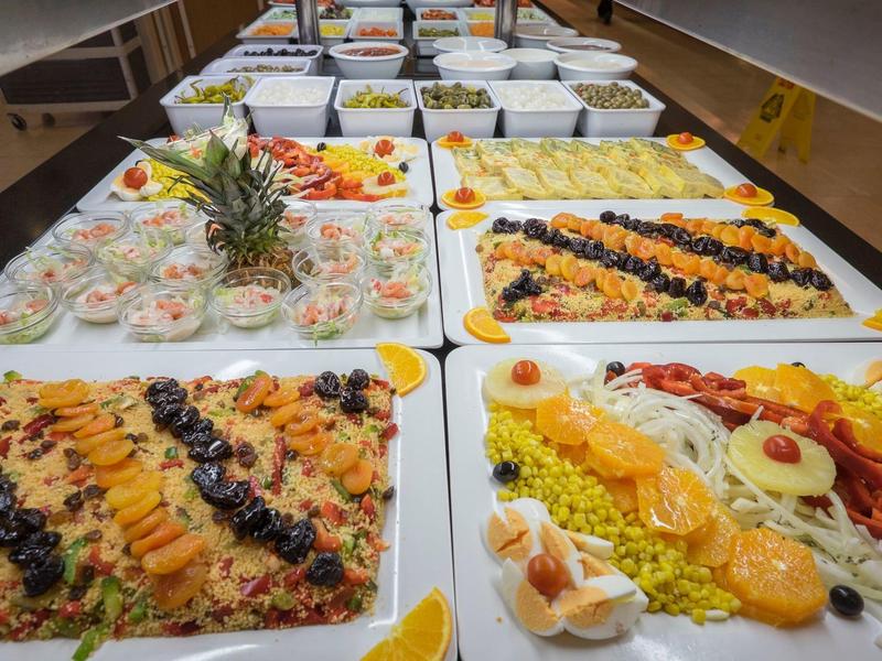 Bufet z różnymi potrawami z ryżu, owocami i dekoracjami na białych tacach.