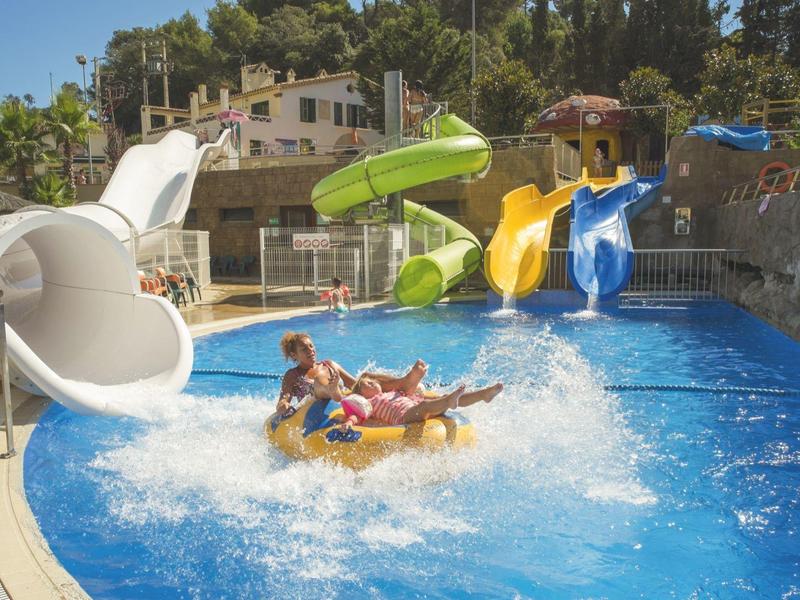 Dzieci i dorośli na pontonie zjeżdżający z wodnych zjeżdżalni na basenie.