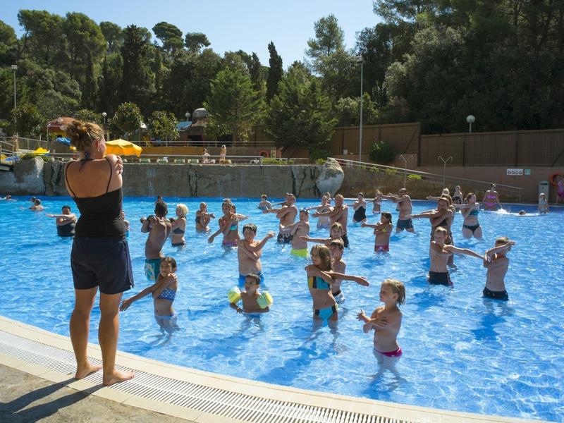Dzieci biorą udział w zajęciach gimnastyki wodnej na zewnętrznym basenie hotelowym.