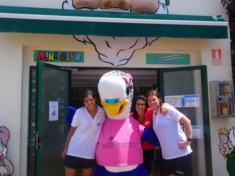 Dwie kobiety pozują przed sklepem z dużą, kolorową statuą kaczki.